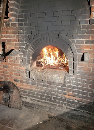 Ein Steinofen in dem ein Holzfeuer brennt.