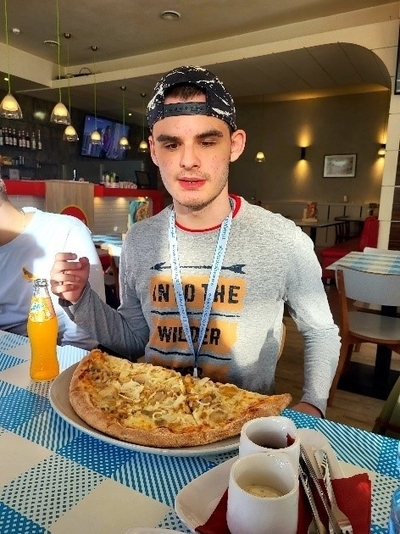 Jugendlicher isst eine große halbe Pizza