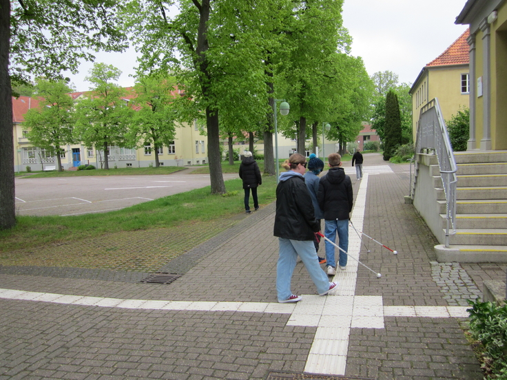 Alle Teilnehmenden gehen mit einem Langstock unter der Augenbinde. Zur Orientierung dient die weiße Leitlinie.