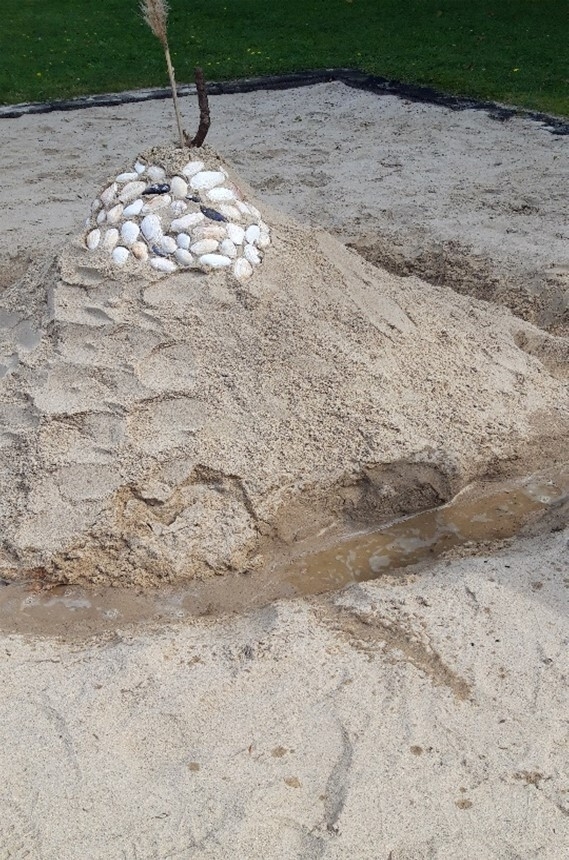 Die fertige Sandburg mit Muschelverzierung und Wassergraben