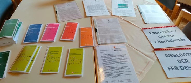 Auf einem Tisch liegen mehrere Informationen und Flyer.