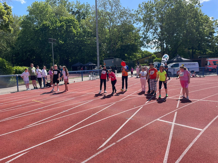 Mehrere Schüler stehen mit ihren Begleitläuferinnen an der Startlinie für den 100 Meter Sprint.