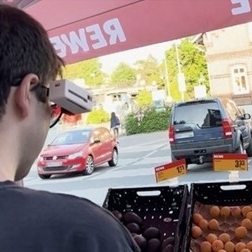 Ein blinder Jugendlicher steht draußen vor einem Stand mit Obst und Gemüse, er trägt den Prototypen.