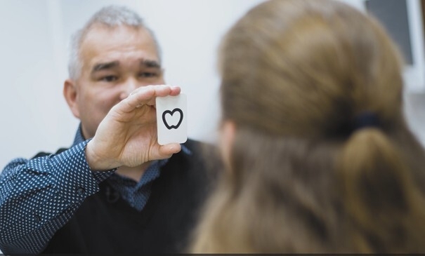Claas Proske hält einer Schülerin eine Karte vor ihr Gesicht.