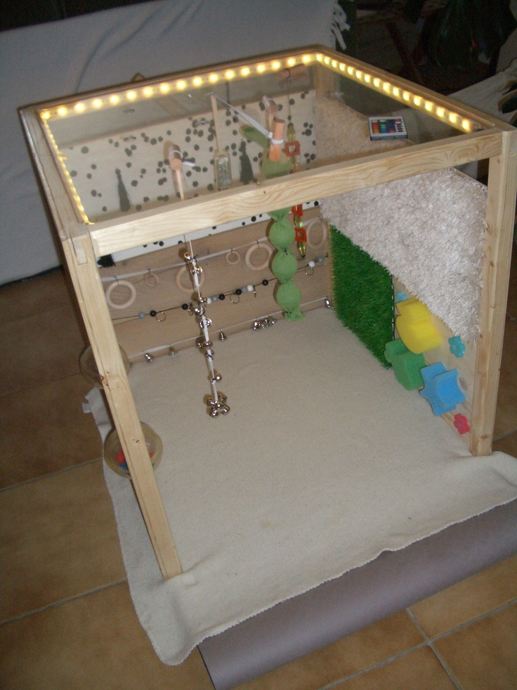 Das Bild zeigt den Nachbau eines „Kleinen Raums“ nach Lilli Nielsen: Drei Seitenwände aus Holz (links, rechts, hinten) sowie eine Plexiglasplatte (oben) bilden einen Würfel, der unten und vorne offen ist.