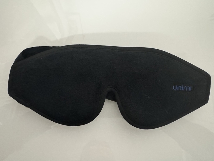 Auf dem Foto ist eine schwarze Augenbinde auf weißem Grund zu sehen.