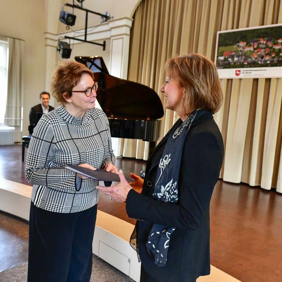Frau Grodzki wird in der Aula des LBZB die Entlassungsurkunde von der Ministerin Frau Behrens überreicht. Im Hintergrund ist der Pianist, Herr Dr. Hribar, am Flügel zu sehen