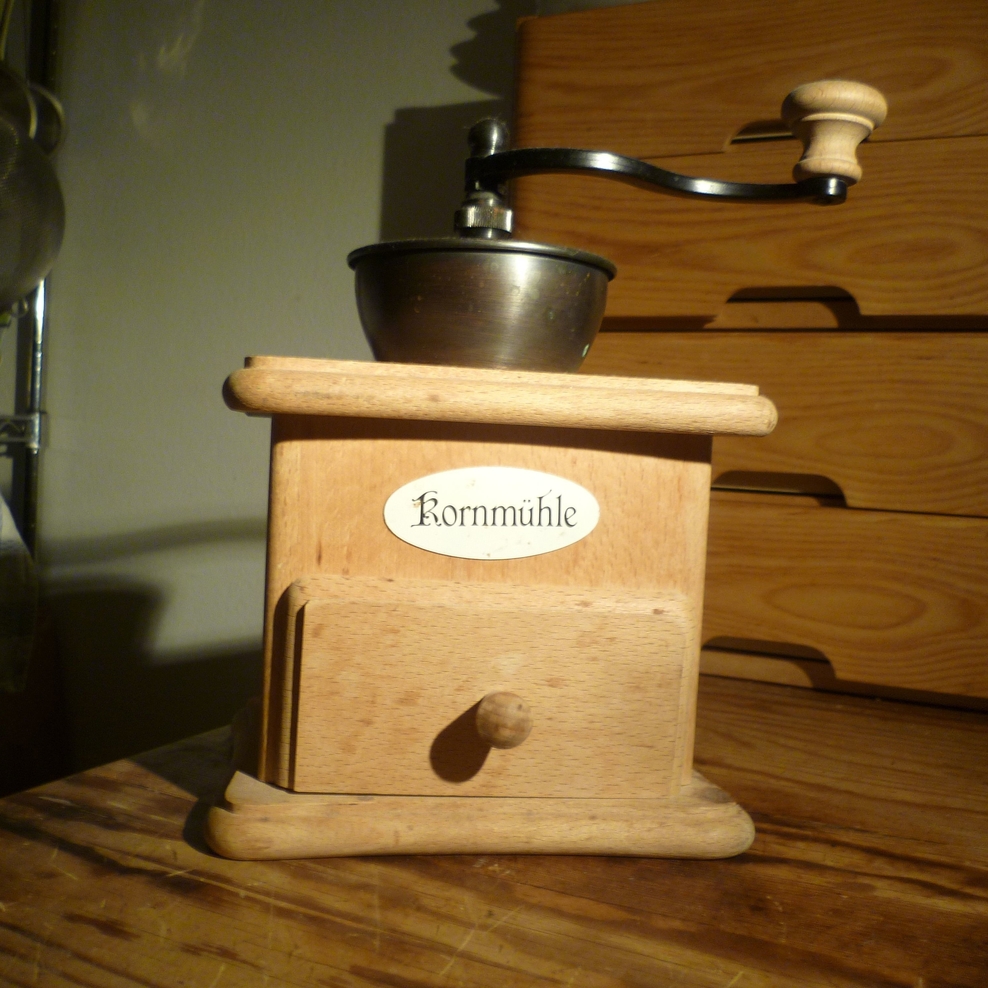 Auf dem Foto ist eine handbetriebene Getreidemühle in der Größe einer Kaffeemühle zu sehen.