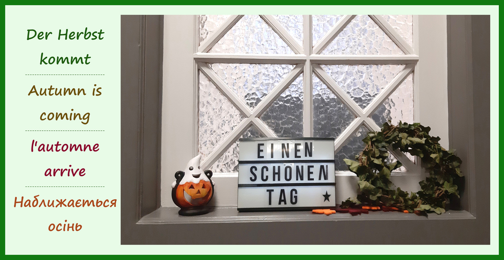 Ein Fensterbrett mit herbstlicher Dekoration, einem Kürbis und ein Schild auf dem steht: Einen schönen Tag.