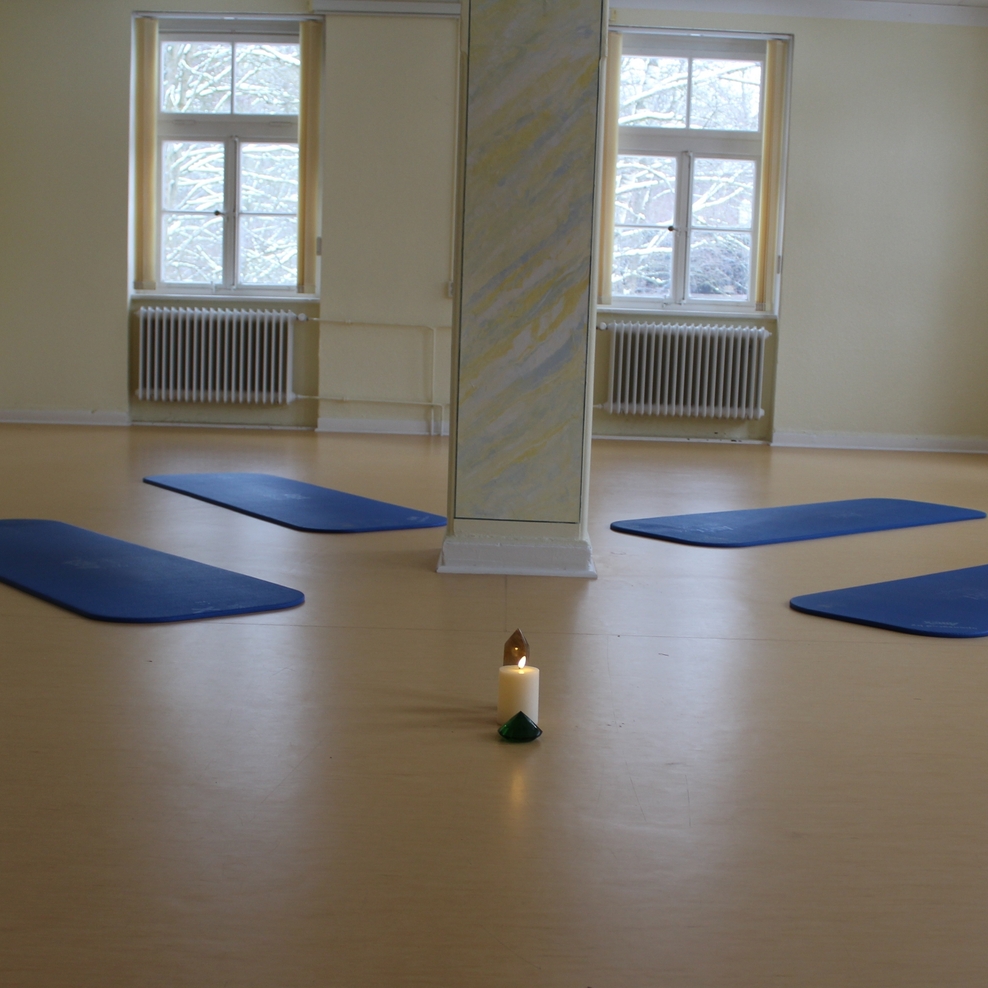 Ein Raum in dem mehrere Yogamatten auf dem Fußboden liegen.